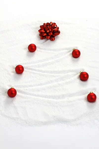 Рождественская ёлка, раскрашенная в снег красным луком и красными матовыми рождественскими шариками — стоковое фото