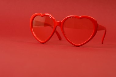 Kırmızı zemin üzerine kırmızı kalp güneş gözlüğü