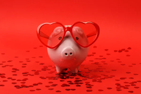 Piggy bank in liefde met rood hart zonnebril permanent op rode achtergrond met glanzende rood hart glitters — Stockfoto