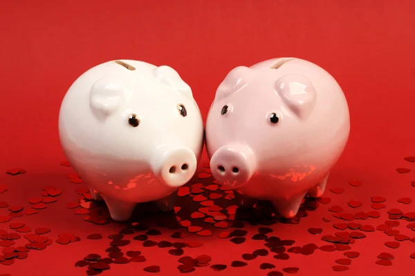 Two Piggies bank in love stading on red background with red shining heart glitters- horizontal — Stock Photo, Image