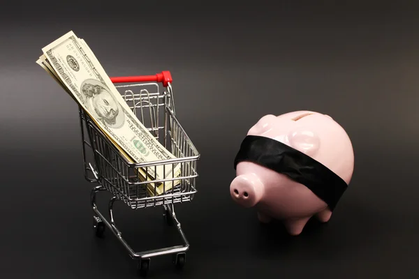 购物篮与钱美国一百张一元钞票内部堆栈和粉红色储钱罐与黑色眼罩站在黑色的背景-水平 — 图库照片