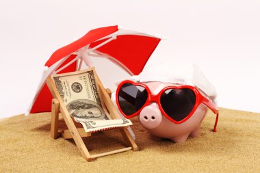 Kum plaj sandalyesini dolar yüz dolardan havlu ile yanındaki kırmızı ve beyaz güneş şemsiyesi altında üzerinde duran kalbi güneş gözlüğü ile yaz piggy banka