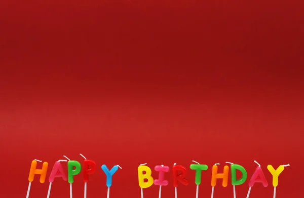 Colorate candele di compleanno felici su sfondo rosso — Foto Stock