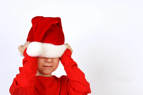 Kerstmis helper kind zetten Santas Claus hoed op hoofd voorzijde van witte achtergrond — Stockfoto