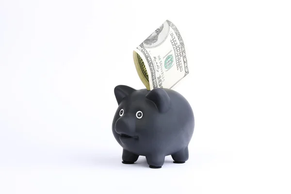 Black Piggy Bank con billete de cien dólares cayendo en la ranura en un fondo de estudio blanco —  Fotos de Stock