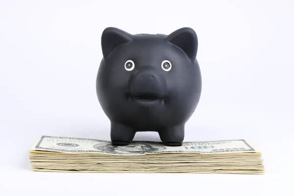 Black Piggy Bank em pé na pilha de dinheiro notas de cem dólares americanos no fundo branco Black Friday, segunda-feira cibernética — Fotografia de Stock