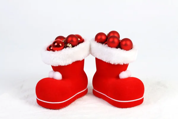Santas shoes full red christmas balls standing on snow — Stock fotografie