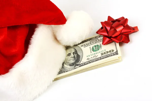Papai Noel chapéu e pilha de dinheiro notas de cem dólares americanos com arco vermelho e no fundo branco — Fotografia de Stock