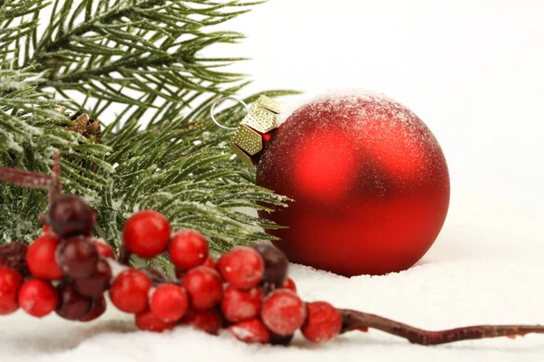 Bola de Natal matt vermelho na neve e rowanberries vermelho — Fotografia de Stock