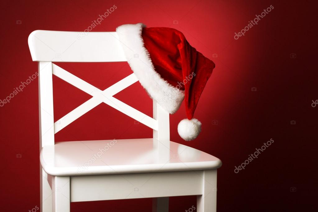 Santa hat on white chair front of red background