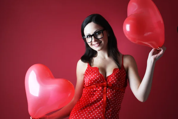 Сексуальная женщина в красном нижнем белье с двумя шариками формы сердца на красном фоне — стоковое фото