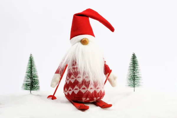 Christmas helper (elf) skiing on snow next two snowy trees Red and white colors — Stock Photo, Image
