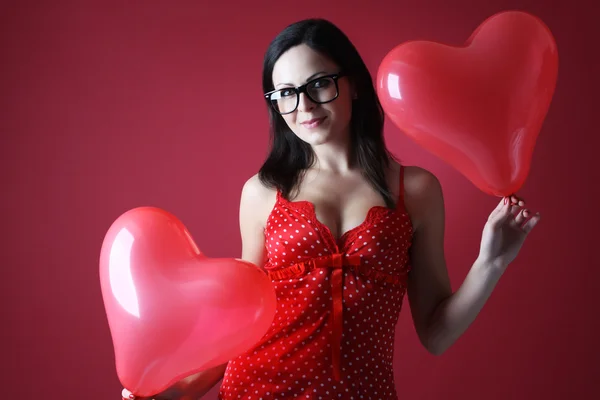 Sexig kvinna i röda underkläder med två ballonger formen hjärta på röd bakgrund alla hjärtans dag — Stockfoto