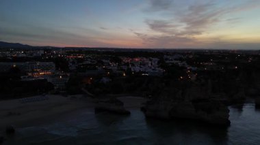 Güneş doğarken güzel Praia dos Tres Irmaos plajının turkuaz okyanus ve manzaralı uçurumlar, Portimao, Portekiz insansız hava aracı görüntüsü. Yüksek kalite 4k görüntü