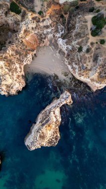 Suyun içinde pürüzlü kayalar olan güzel bir saklanma yeri. Portekiz 'in Algarve bölgesindeki Praia dos Tres Irmaos. Yüksek kalite fotoğraf