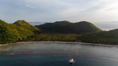 Bayang Basecamp ya da Calibangan Kampı 'nın insansız hava aracı görüntüsü ve Calibangbangan Adası kıyısı boyunca Coron ve El Nido, Palawan, Filipinler arasında turkuaz resifi. Bu, Coron ve El Nido ile Büyük D arasındaki keşif gezisinin temel direktörlerinden biriydi.