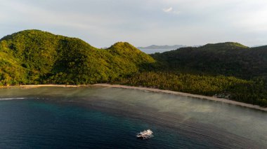 Bayang Basecamp ya da Calibangan Kampı 'nın insansız hava aracı görüntüsü ve Calibangbangan Adası kıyısı boyunca Coron ve El Nido, Palawan, Filipinler arasında turkuaz resifi. Bu, Coron ve El Nido ile Büyük D arasındaki keşif gezisinin temel direktörlerinden biriydi.