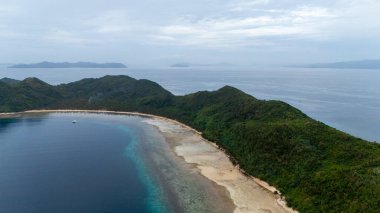 Bayang Basecamp ya da Calibangan Kampı 'nın insansız hava aracı görüntüsü ve Calibangbangan Adası kıyısı boyunca Coron ve El Nido, Palawan, Filipinler arasında turkuaz resifi. Bu, Coron ve El Nido ile Büyük D arasındaki keşif gezisinin temel direktörlerinden biriydi.