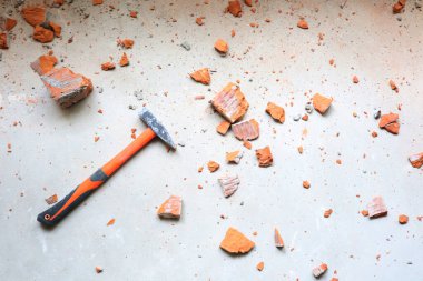 Kırık sarı tuğla parçaları çekiçle çimentoda.