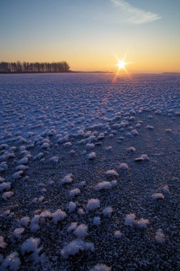 Güneşin arka planında karla kaplı donmuş bir nehir..