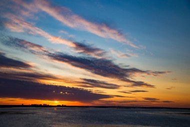Nehirde gün batımı. Nehir ve mavi gökyüzü renkli bulutlarla dolu renkli bir manzara. Nehir batımı manzarası.