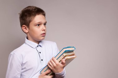 Elinde bir yığın kitap tutan okul çocuğu.