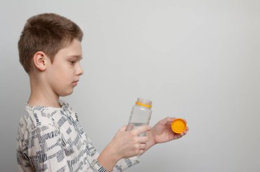 Çocuk plastik bir su şişesini açıyor.