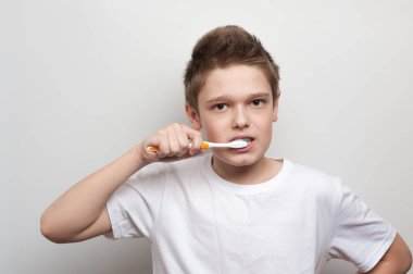 Çocuk diş fırçası ve diş macunu kullanarak dişlerini temizliyor. Diş ve ağız bakımı