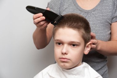Saç kesme makinesi kullanan sarışın bir çocuğun saç kesimi.
