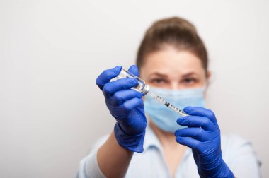 Tıbbi eldivenli bir hemşire şırıngaya aşı ya da ilaç enjekte etmek için arama yapıyor.