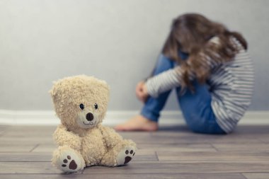 Psikolojik sağlık konsepti. Oyuncak ayı ve arka planda odak noktasından çıkmış genç bir kız. Çocuklara ve ergenlere psikolojik yardım