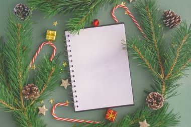Noel arka planında ağaçlardan, oyuncaklardan ve Noel şekerlerinden yapılmış boş beyaz bir defter. Yılın planları yazılıyor, özetleniyor, yeni yıl hazırlıkları yapılıyor..