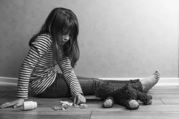 Üzgün bir genç kız evde tabletlerin, oyuncak ayının ve telefonun yanında oturuyor. Çocuk depresyonu ve psikolojik sorunlar. Yumuşak odak.