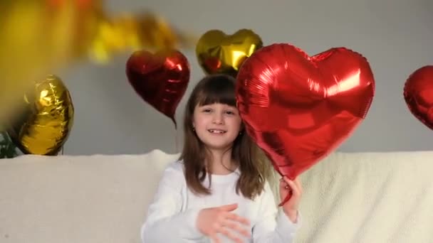 Alla hjärtans dag video. Söt liten kaukasisk flicka kastar guld och röda hjärtformade ballonger. En glad semester för alla älskare — Stockvideo