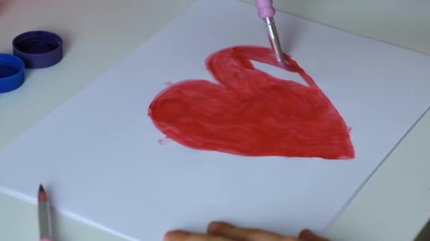 子供の女の子は赤い塗料で心をペイントします。バレンタインデー、父と母の日、愛のサイン。スローモーション — ストック動画