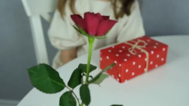 Een leuke jongen geeft een donkerharig mooi meisje bloemen, een rode roos. Cadeaus voor de vakantie, bloemen voor Valentijnsdag. Langzame beweging. — Stockvideo