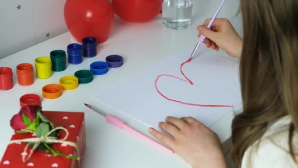 Meisje schildert een hart met rode verf als geschenk voor Valentijnsdag. Liefde teken. Cadeaus voor kinderen. Schilderen met verf. Langzame beweging — Stockvideo