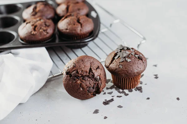 Hemgjorda chokladmuffins eller muffins, utsmyckade med chokladchips, på ett ljust bord. Hembakade bakverk eller bakverk till frukost eller fest — Stockfoto