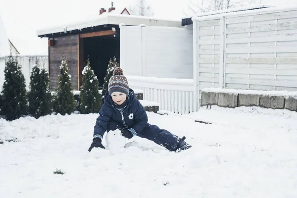 Giochi sulla neve, vacanze invernali, vacanze in famiglia. Carino ragazzo caucasico che gioca nella neve nel cortile della casa — Foto Stock
