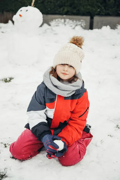 Ritratto di una bella e carina adolescente nella neve nel cortile di casa. Vacanze invernali, giochi per bambini — Foto Stock