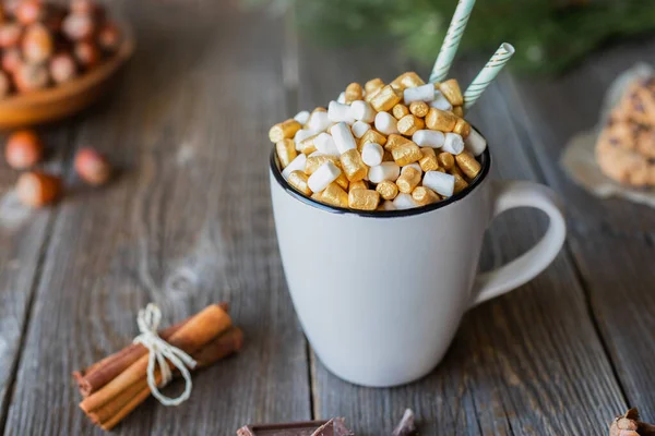 Ein Becher mit heißer Schokolade oder Kakao, verziert mit Gold und weißen Marshmallows, auf einem Holztisch. Platz für Ihren Text. Heißer Herbst und Winterdrink — Stockfoto