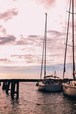 İskelede gün batımı ya da gün doğumu. Güneşin doğuşunda tekneli bir iskele. Denizde balıkçı tekneleri