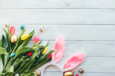 Beyaz ahşap arka planda lale çiçeklerinin, yumurtaların ve tavşan kulaklarının Paskalya yerleşimi. Bahar, şenlikli düzlük. Boşluğu kopyala