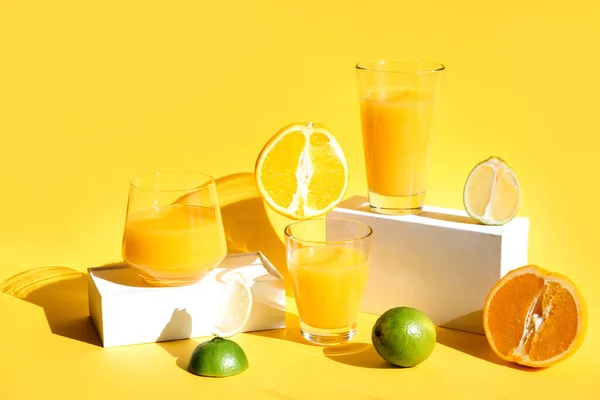 Succo d'arancia appena spremuto su passerelle bianche con ombre dure su uno sfondo giallo. Cibo sano e bevande concetto creativo. Copia spazio — Foto Stock
