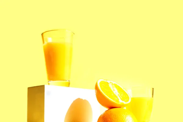 Jugo de naranja fresco y jugoso en vasos en pasarelas blancas de moda con sombras duras sobre un fondo amarillo. Concepto de comida y bebida saludable. Copiar espacio —  Fotos de Stock