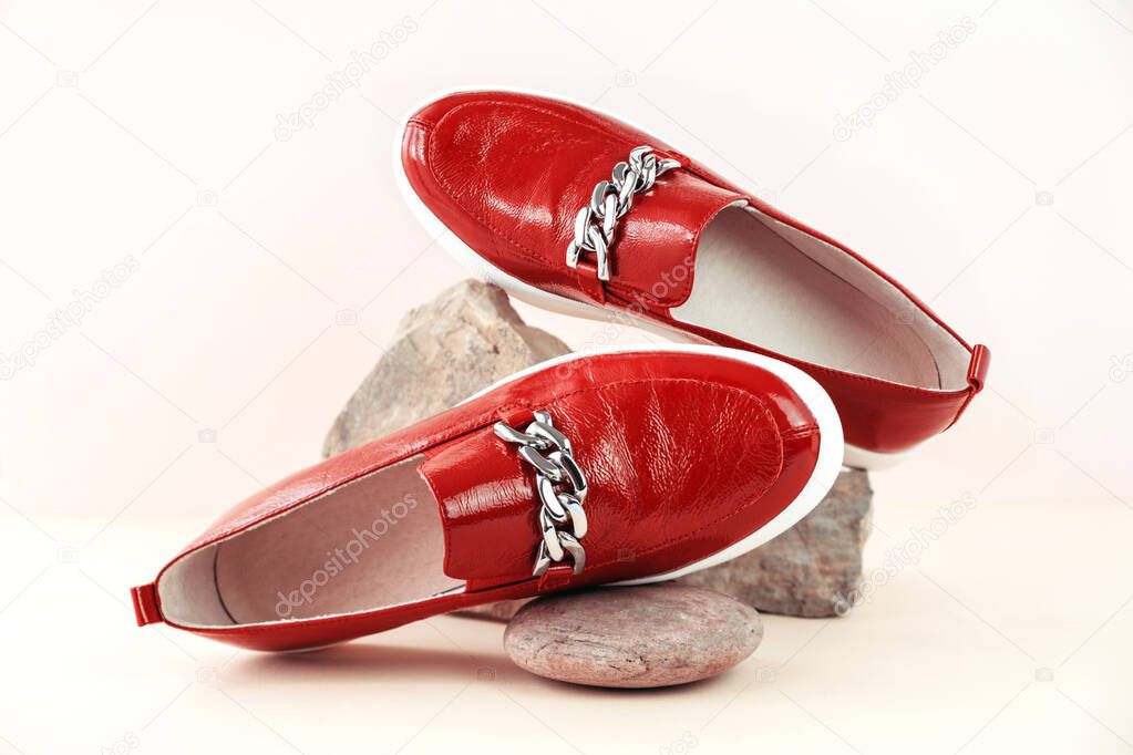 Fashion and stylist concept. Red loafers, boots or moccasins on a stone podium on a neutral background with place for text. Ideal for illustrating articles