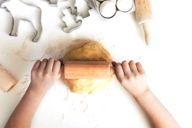 Yeni yıl ya da Noel aşçılığı konsepti. Kız beyaz bir masaya kurabiye hamuru serer. Tatil için en iyi manzara hazırlanıyor