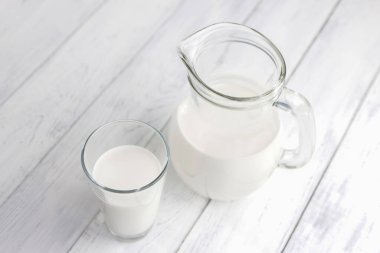 Bir bardak süt, yoğurt ya da kefir dolu bir sürahinin yanında. Mayalanmış yiyecekler. Alternatif sebze sütü.