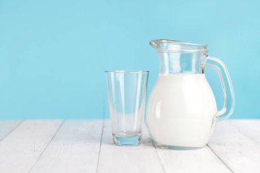 Taze inek, sebze sütü, kefir, yoğurt ve yanında bir bardak beyaz tahta masa. Metin için yer