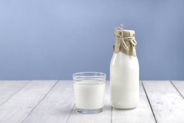 A glass with kefir, homemade yogurt or vegetable milk on a white table and next to a bottle with a drink. Space for text, horizontal photo